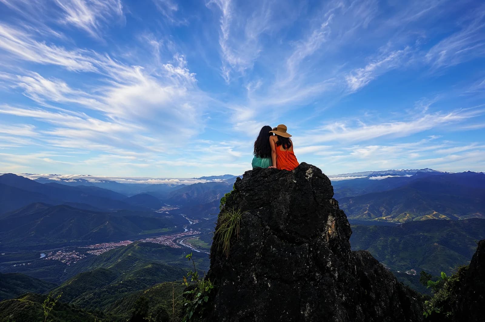 Dos personas sentadas sobre la roca del mirador Los Antis frente al valle de Chanchamayo